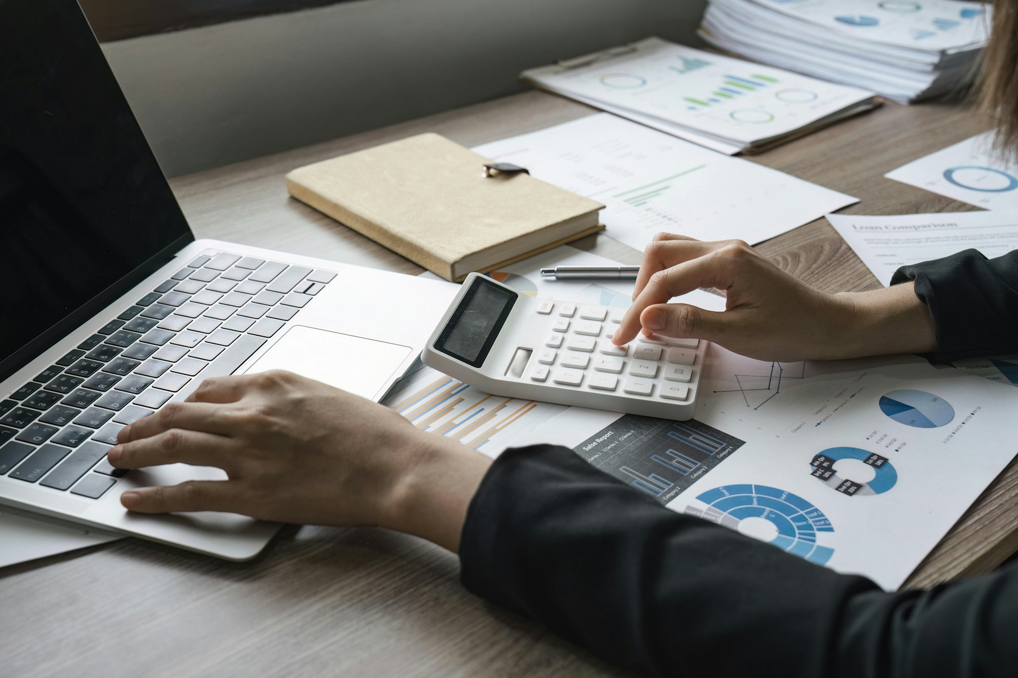 Bookkeeper using a calculator to calculate numbers on a company's financial documents, he is