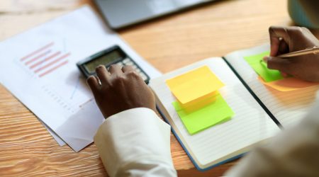 Black woman hands working on monthly budget, using calculator